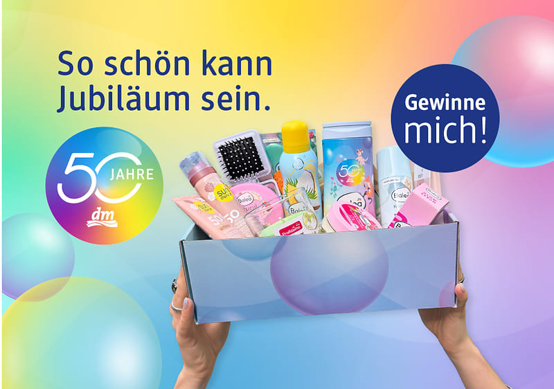 Bunte Geschenkbox mit Pflegeprodukten und Überraschungen, gehalten von zwei Händen, links Slogan „So schön kann Jubiläum sein.“, darunter rundes Logo „50 Jahre dm“, rechts blauer Kreis mit Text „Gewinne mich!“