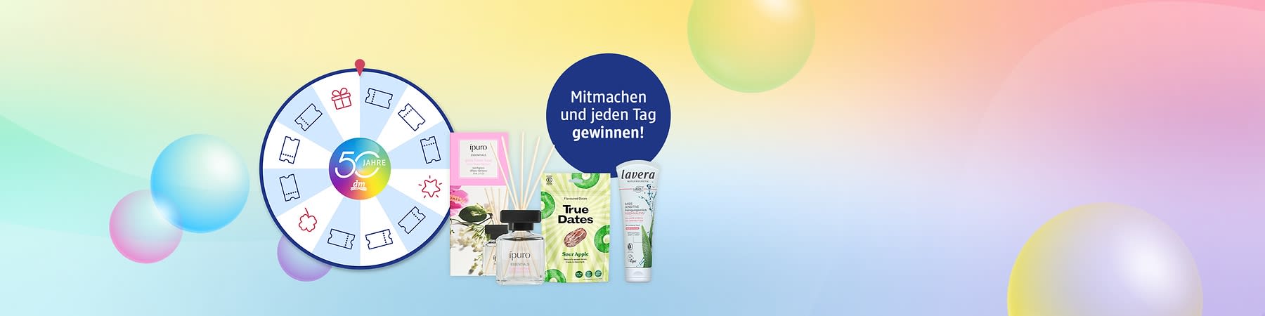 Glücksrad mit buntem Mittelkreis „50 Jahre dm“, Pfeil und Gewinnfeldern, rechts Duftstäbchen, ipuro Raumduftbox, True Dates Snack „Sour Apple“ und lavera Handcreme, blauer Kreis „Mitmachen und jeden Tag gewinnen!“