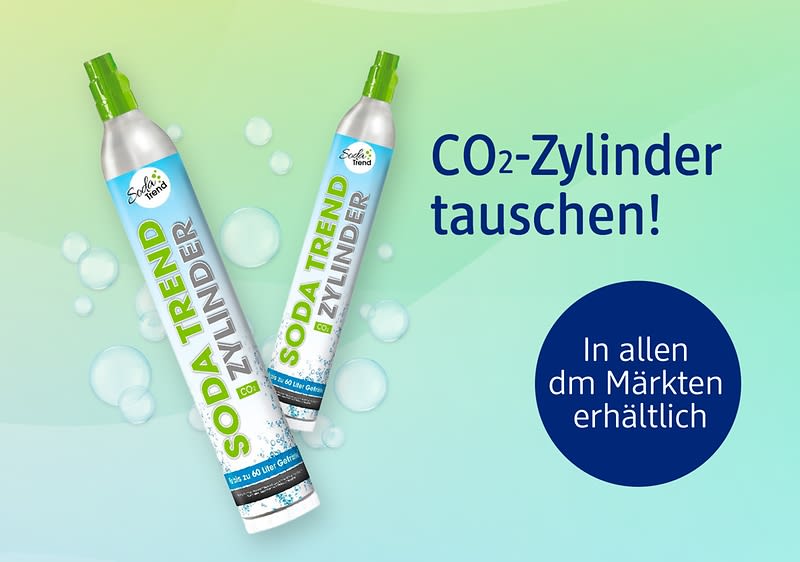 Zwei silberne CO2-Zylinder mit grünem Sprühkopf und Aufschrift „SODA TREND ZYLINDER“ vor grün-blauem Hintergrund, rechts Text „CO2-Zylinder tauschen!“ und blauer Kreis mit „In allen dm Märkten erhältlich“