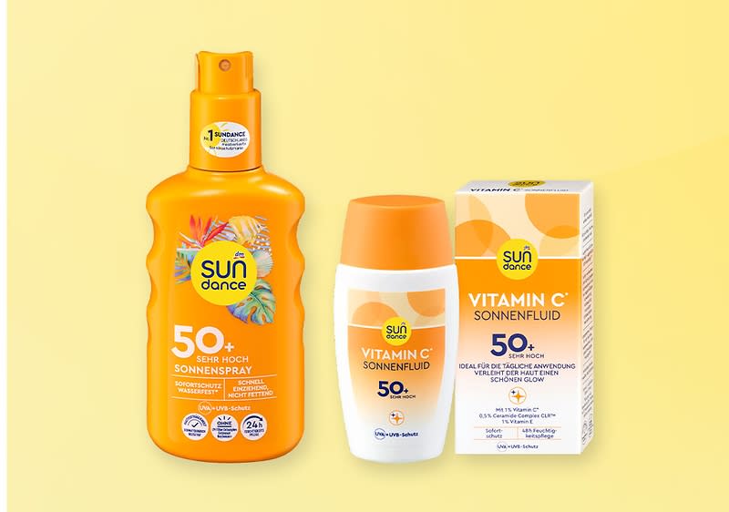 Drei orange-weiße Sundance Sonnenschutzprodukte nebeneinander: links eine Sprühflasche „Sundance 50+ Sehr Hoch Sonnenspray“, mittig eine kleine Flasche „Sundance Vitamin C Sonnenfluid 50+“, rechts die zugehörige Verpackung mit Aufschrift „Vitamin C Sonnenfluid 50+“