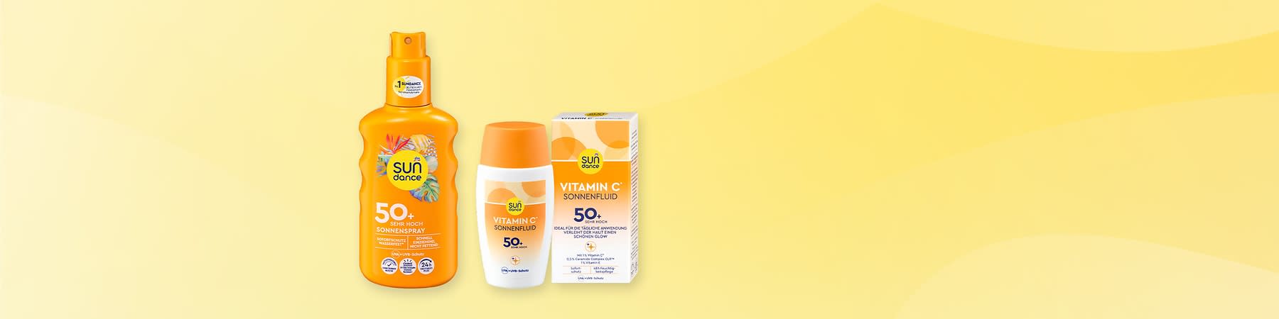 Drei orange-weiße Sundance Sonnenschutzprodukte nebeneinander: links eine Sprühflasche „Sundance 50+ Sehr Hoch Sonnenspray“, mittig eine kleine Flasche „Sundance Vitamin C Sonnenfluid 50+“, rechts die zugehörige Verpackung mit Aufschrift „Vitamin C Sonnenfluid 50+“