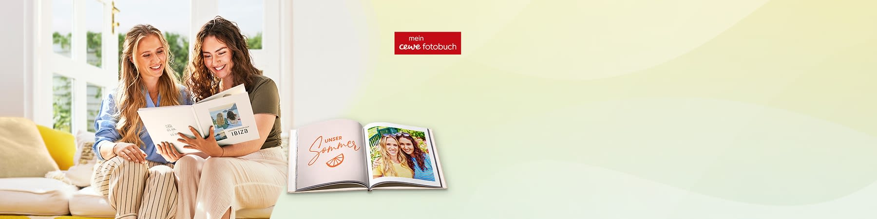 Zwei lächelnde Frauen sitzen nebeneinander und blättern in einem Fotobuch, davor ein aufgeklapptes Fotobuch mit dem Schriftzug „UNSER Sommer“ und einem Foto der beiden auf der rechten Seite, oben rechts das rote Logo „mein cewe fotobuch“