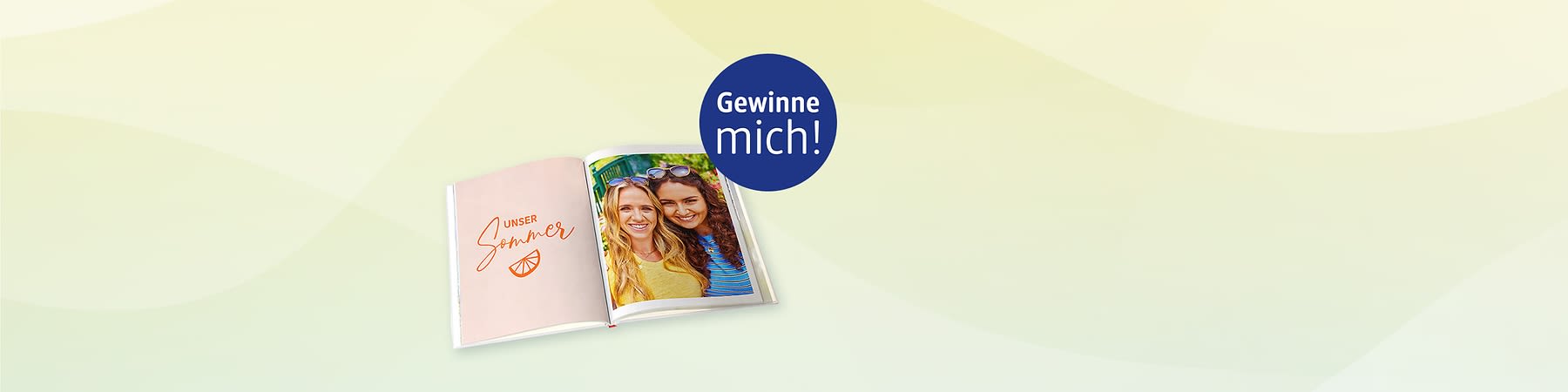 Aufgeschlagendes Fotobuch, linke Seite rosa mit Schrift „UNSER Sommer“ und einer kleinen Orangenscheibe, rechte Seite Foto zweier lächelnder Frauen nebeneinander, oben rechts blauer Kreis mit weißer Aufschrift „Gewinne mich!“