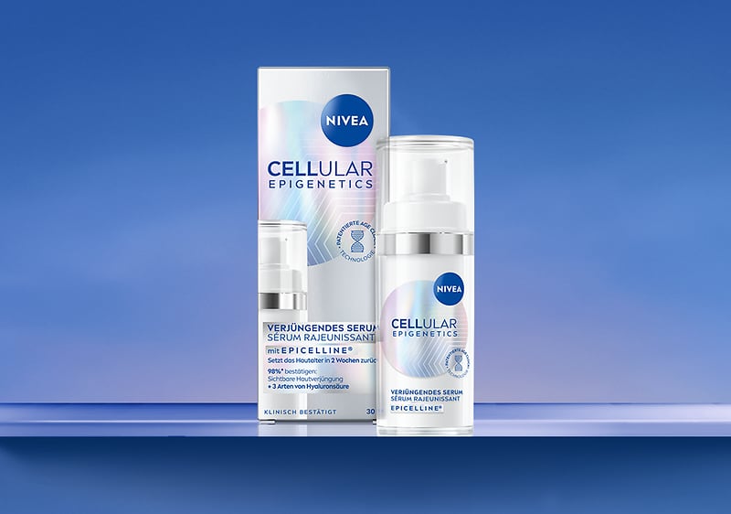 Zwei weiß-blaue NIVEA Cellular Epigenetics Produkte nebeneinander: links die rechteckige Kartonverpackung mit Markenlogo und dem Schriftzug „CELLULAR EPIGENETICS“, rechts die passende Pumpspender-Flasche mit transparentem Deckel und gleichem Design, auf blauem Hintergrund