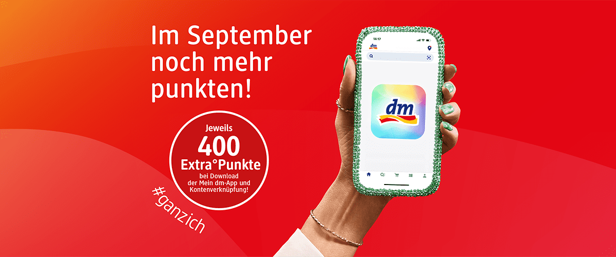 Rote Werbegrafik mit der Aufschrift „Im September noch mehr punkten!“ links, darunter ein weißer Kreis mit „Jeweils 400 Extra°Punkte bei Download der Mein dm-App und Kontenverknüpfung!“ und dem Hashtag „#ganzich“, rechts eine Hand mit grüner Nagellack-Maniküre hält ein Smartphone mit der bunten dm-App-Ikone ohne Punkt am Ende
