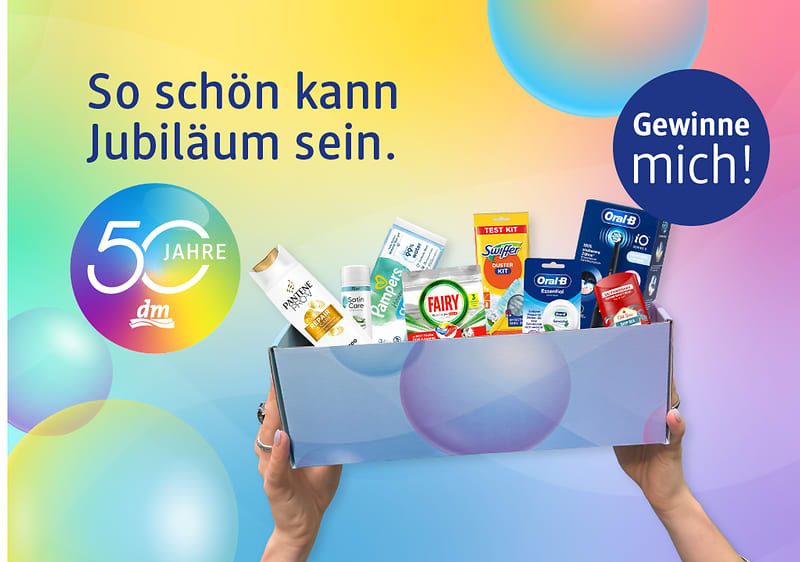 Bunte Jubiläumswerbung mit dem Text „So schön kann Jubiläum sein“, dem runden Logo „50 Jahre dm“ links und einem blauen Kreis rechts mit „Gewinne mich!“, in dessen Mitte Hände eine Geschenkbox mit verschiedenen Drogerieprodukten wie Zahnpasta, Shampoo, Waschmittel und Putzmittel halten
