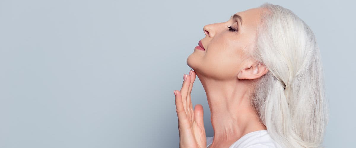 Ältere Frau streicht sich über den Hals