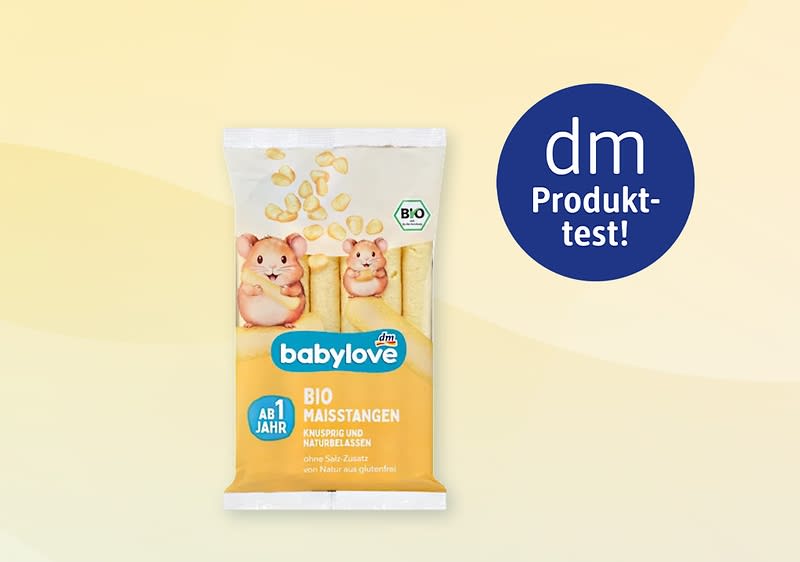 Packung babylove Bio-Maisstangen gelb-weiß mit zwei gezeichneten Hamsterfiguren, Aufschrift „babylove“, „BIO MAISSTANGEN“, „AB 1 JAHR“ und dm-Produkt-test!-Badge rechts oben