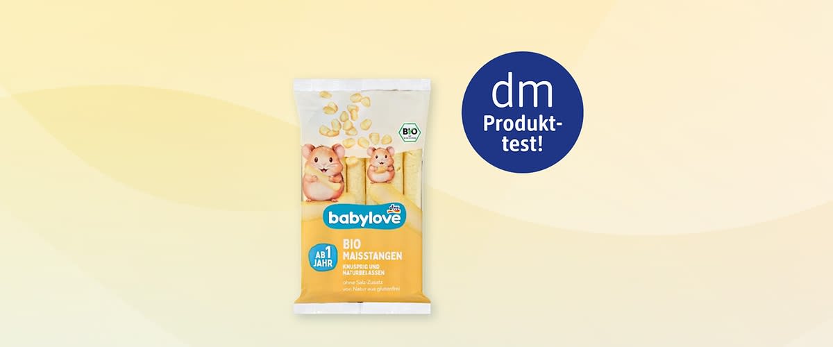Packung babylove Bio-Maisstangen gelb-weiß mit zwei gezeichneten Hamsterfiguren, Aufschrift „babylove“, „BIO MAISSTANGEN“, „AB 1 JAHR“ und dm-Produkt-test!-Badge rechts oben