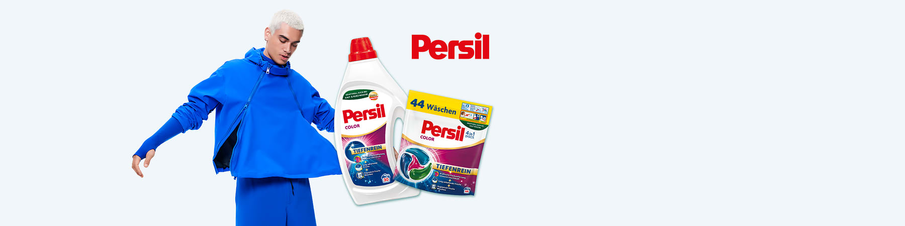 Junger Mann in blauem Outfit dreht sich leicht, daneben eine weiße Persil-Color Flüssigflasche mit rotem Verschluss und ein Persil-Color Waschmittelpods-Paket mit Aufschrift „44 Wäschen“ und dem roten Persil-Logo