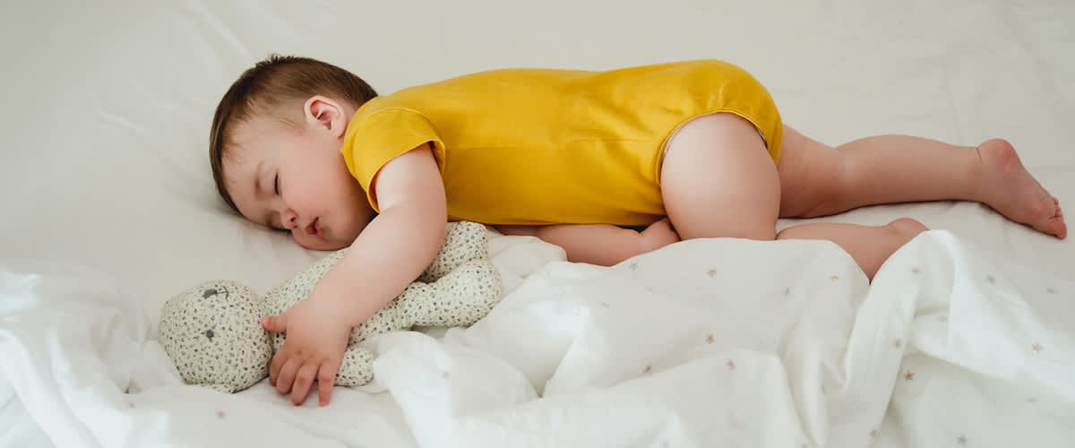 Baby schläft neben Teddybär