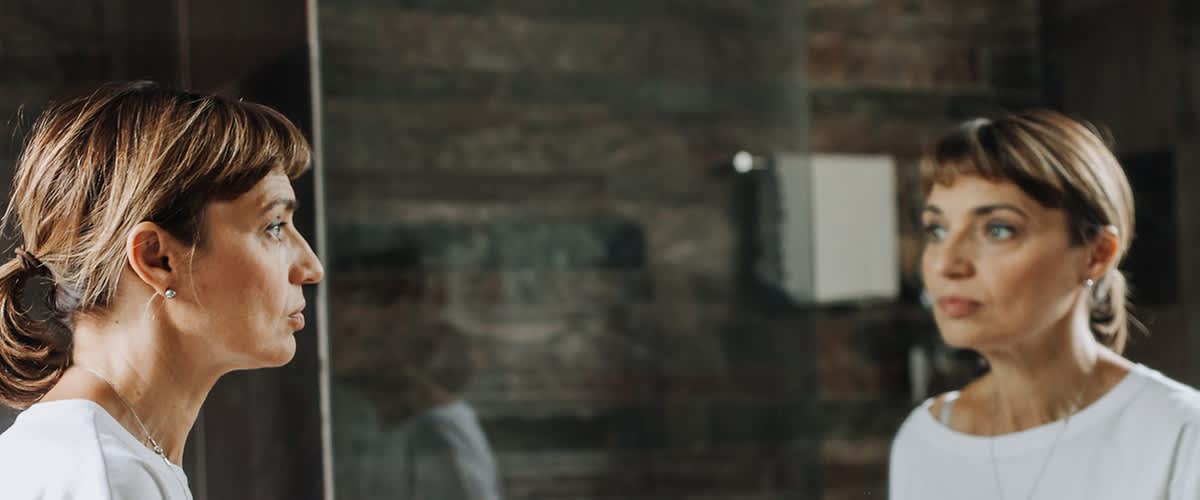 Frau die verzweifelt in den Spiegel schaut 