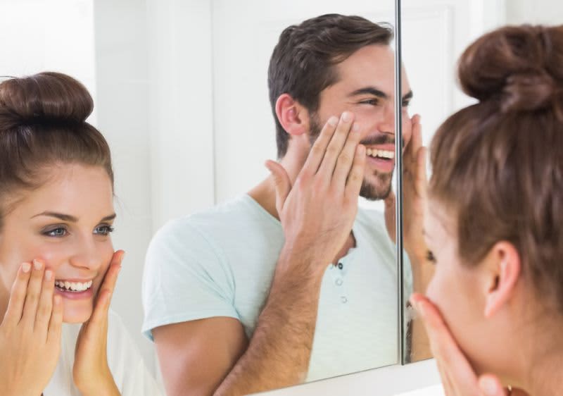 Mann und Frau bei der Gesichtspflege im Badezimmer.