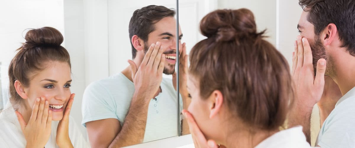 Mann und Frau bei der Gesichtspflege im Badezimmer.