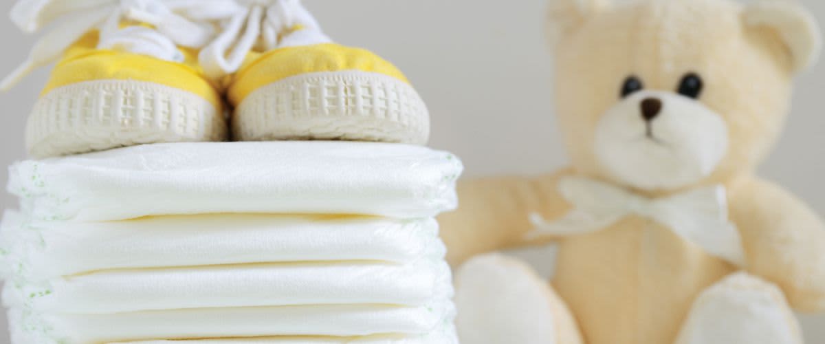 Windeln, Babyschuhe und ein Teddybär.