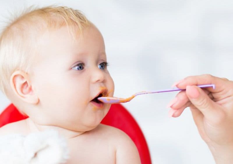 Ein Baby bekommt einen Löffel Brei.
