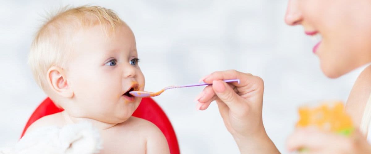 Ein Baby bekommt einen Löffel Brei.