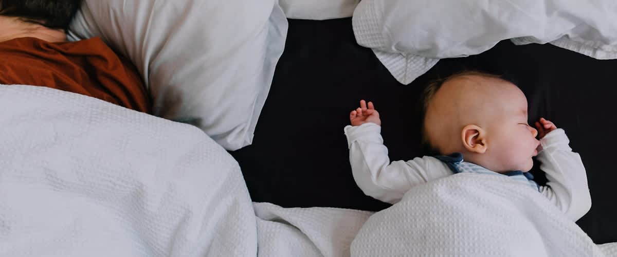 Baby liegt gut zugedeckt im Bett