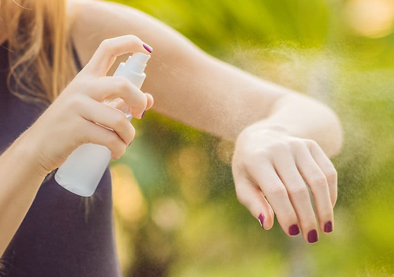 Frau, die sich mit Insektenschutz einsprüht