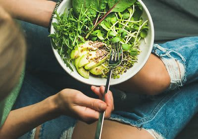 Frau mit Salatschüssel in der Hand beim Essen