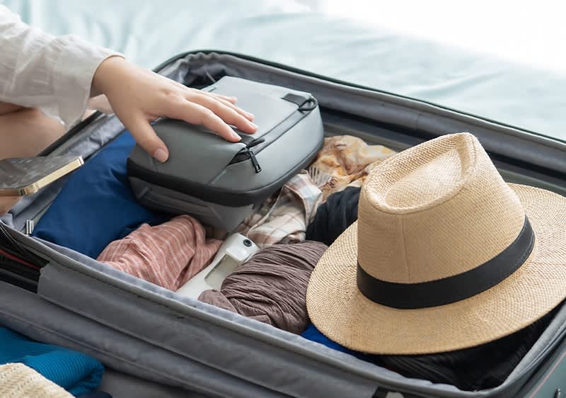 Kofferpacken mit Kleidung und Strohhut