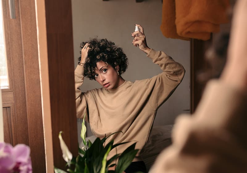 Haarstyling im Spiegel mit Pflanze im Vordergrund
