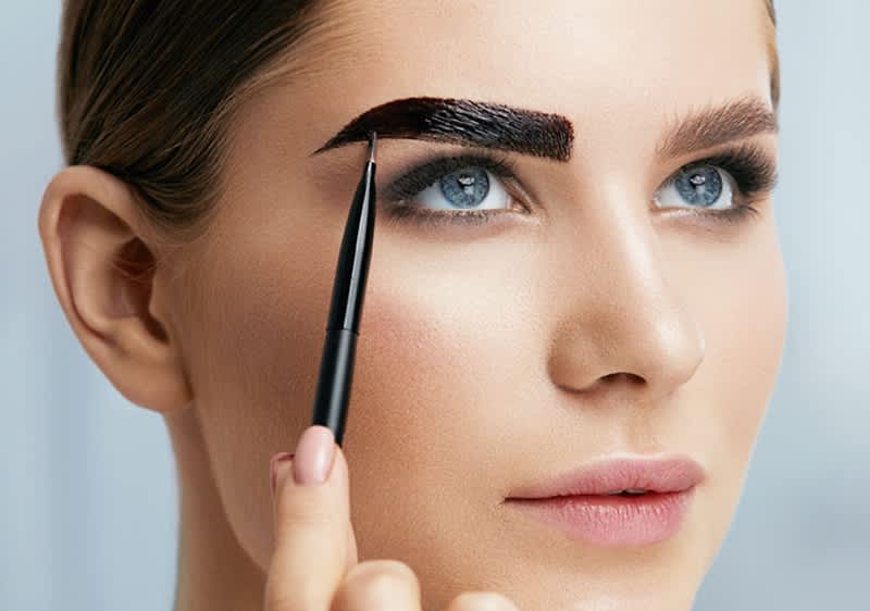 Frau färbt sich die Augenbrauen