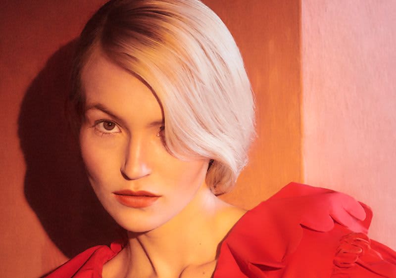 Blonde Frau vor rotem Hintergrund.