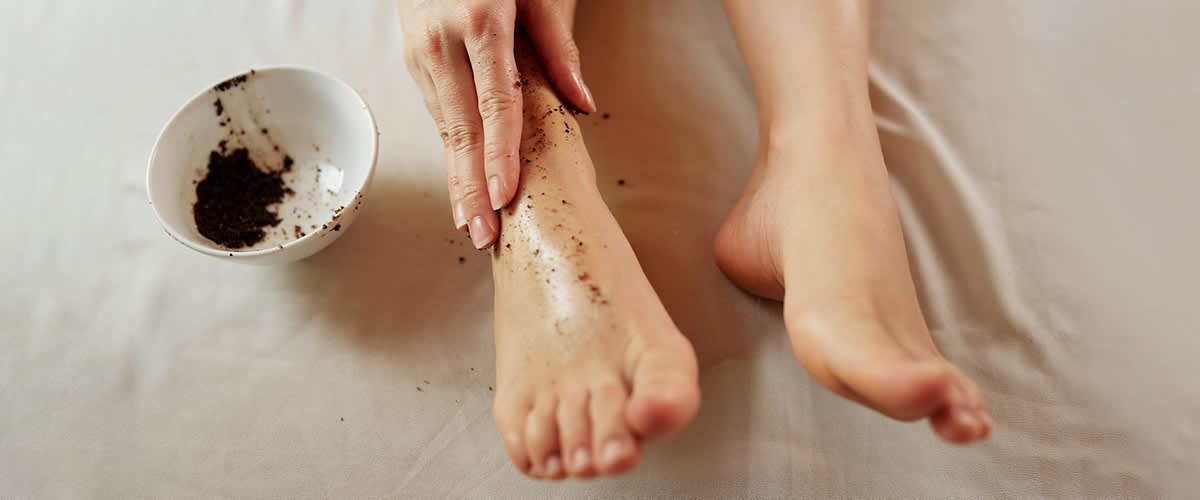 Frau cremt Füße mit Fußpeeling ein