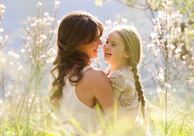 Frau mit Kind sitzt auf blühender Wiese