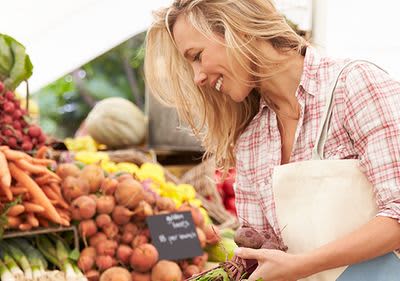 Frau kauft saisonales Obst und Gemüse ein. 