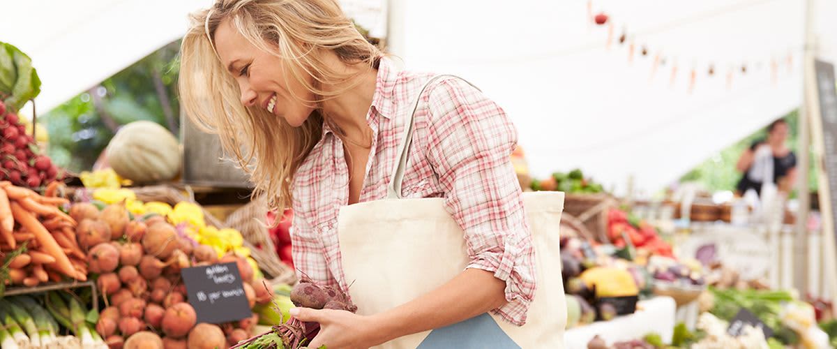 Frau kauft saisonales Obst und Gemüse ein.