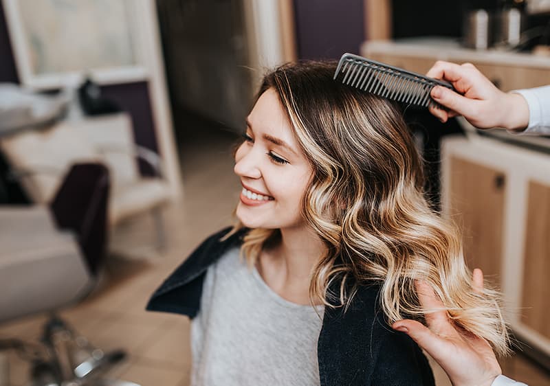 Friseur kämmt blondes Haar im Salon