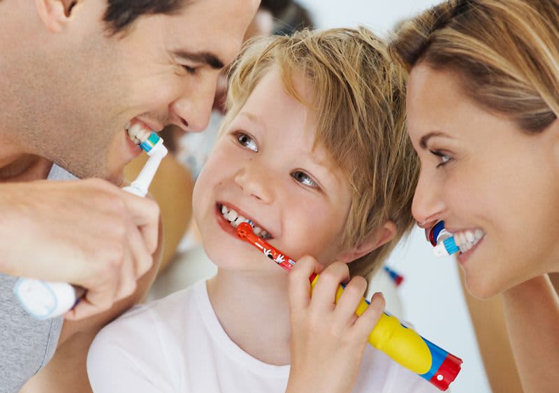 Familie putzt mit elektrischer Zahnbürste die Zähne