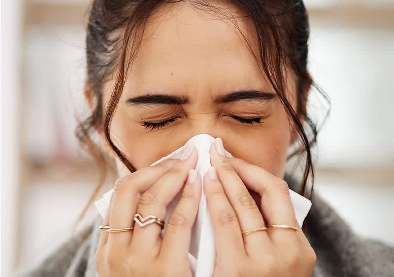 Verschnupfte Frau mit Taschentuch