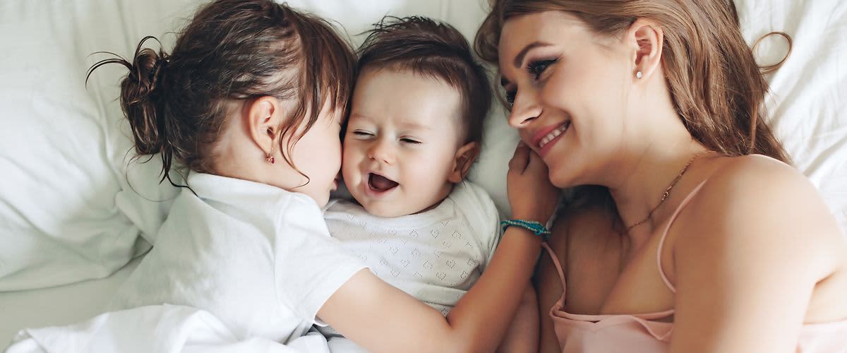 Mama liegt mit ihren Kindern im Bett