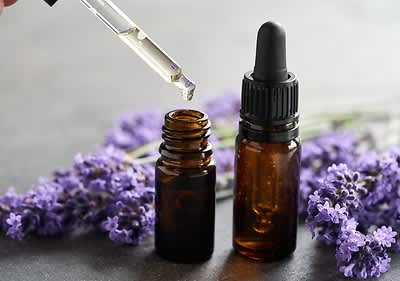 Lavendelöl mit Pipette und Lavendelblüten im Hintergrund