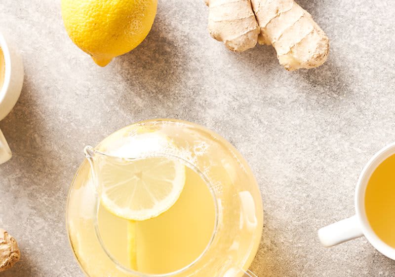 Kanne und Tasse mit Tee, Zitronen, Ingwer