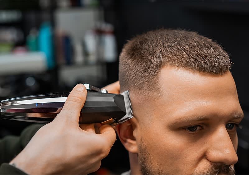 Haarschnitt mit Haarschneidemaschine im Friseursalon