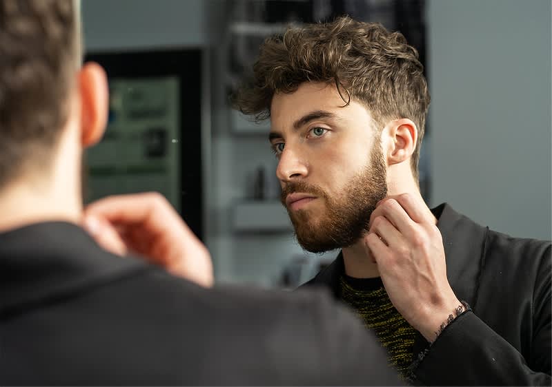 Mann im Spiegel mit verschwommenem Gesicht und lockigem Haar