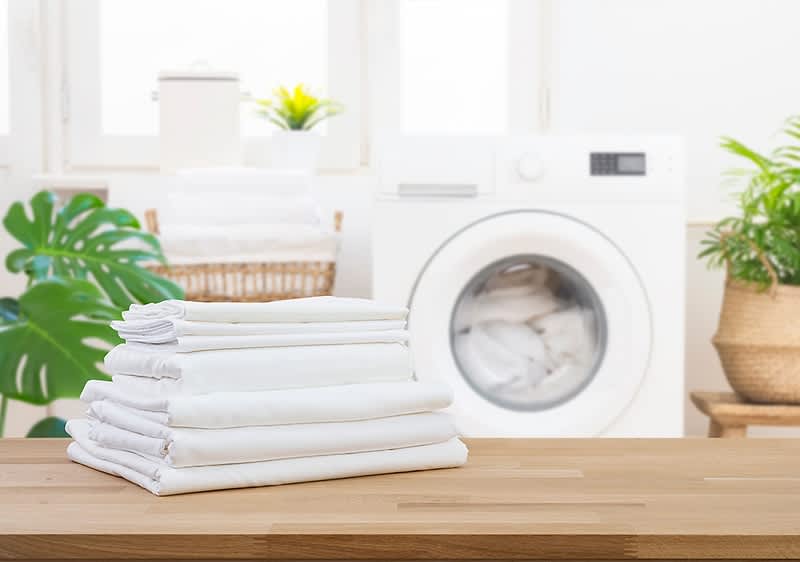 Wäschepflege im Waschraum mit gefalteten weißen Handtüchern und Waschmaschine