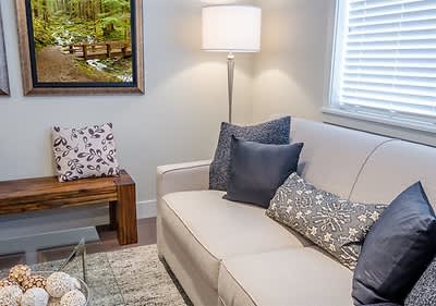 Wohnzimmer mit Sofa und Kissen neben Lampe und Fenster mit Bild an der Wand