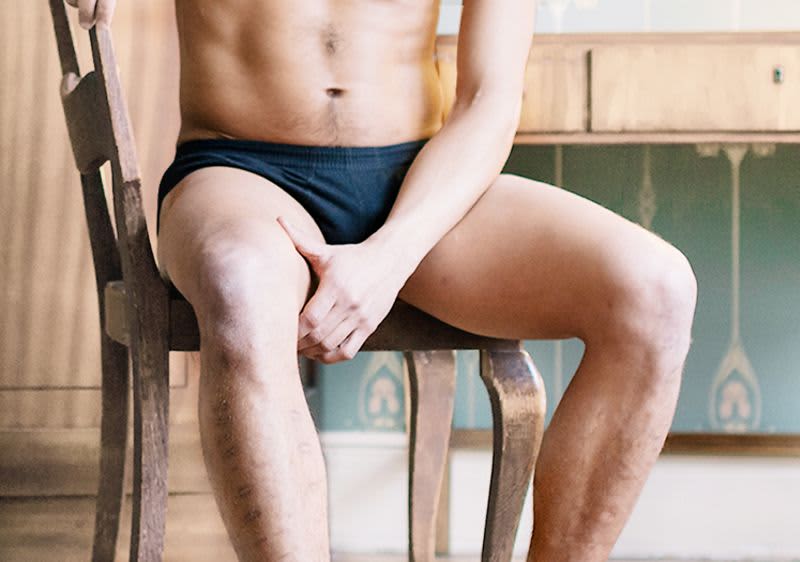 Mann in Unterwäsche auf Stuhl sitzend