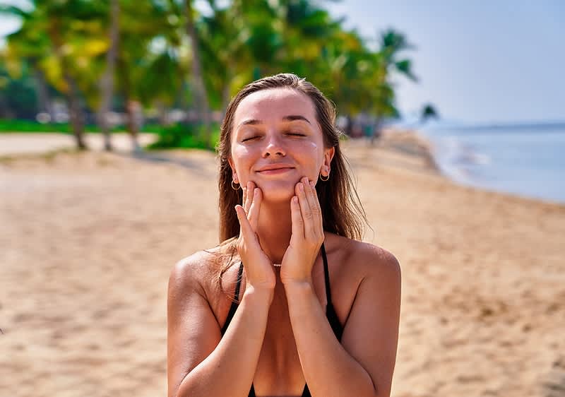 Frau am Strand mit Palmen und Meer im Hintergrund