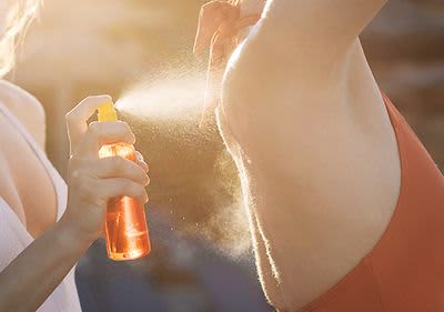 Sonnencreme wird auf Haut gesprüht im Sonnenlicht