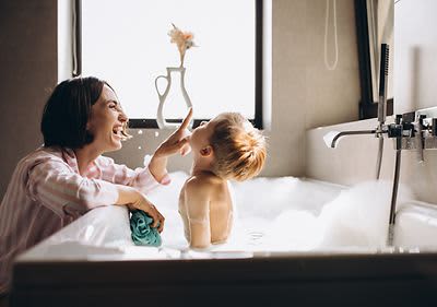Mama lacht mit Sohn in der Badewanne