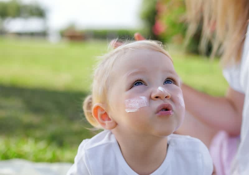 Kind im Freien mit grünem Hintergrund und unscharfem Gesicht