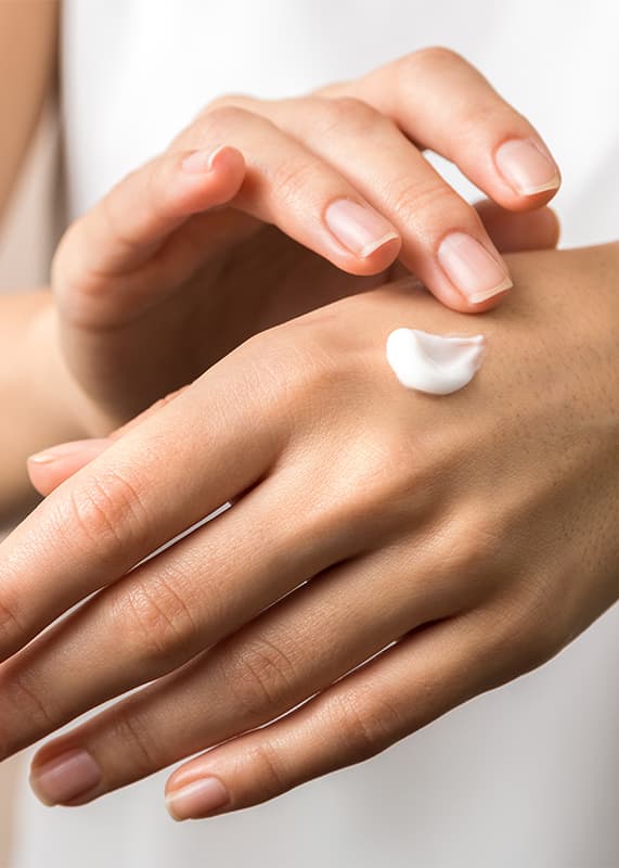 Frau cremt sich die Hände ein