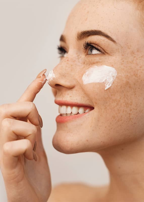 Frau cremt sich das Gesicht ein