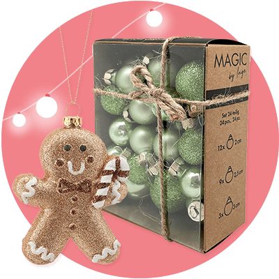 Eine Verpackung mit der Aufschrift „MAGIC by hope“ enthält grüne Weihnachtskugeln in verschiedenen Größen, daneben ein glitzernder Lebkuchenmann-Anhänger mit Zuckerstangen-Dekoration